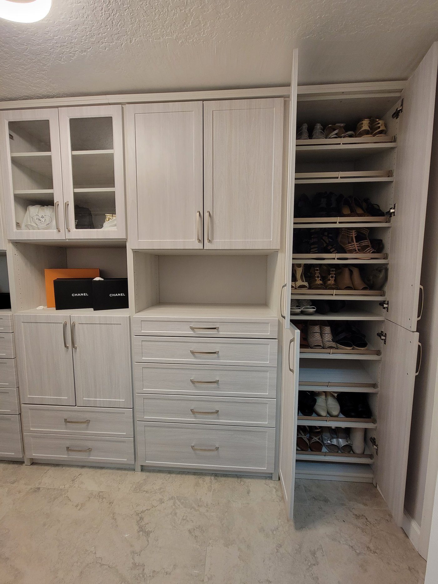 Woodgrain closet with glass-front cabinets and shoes by Create More Space