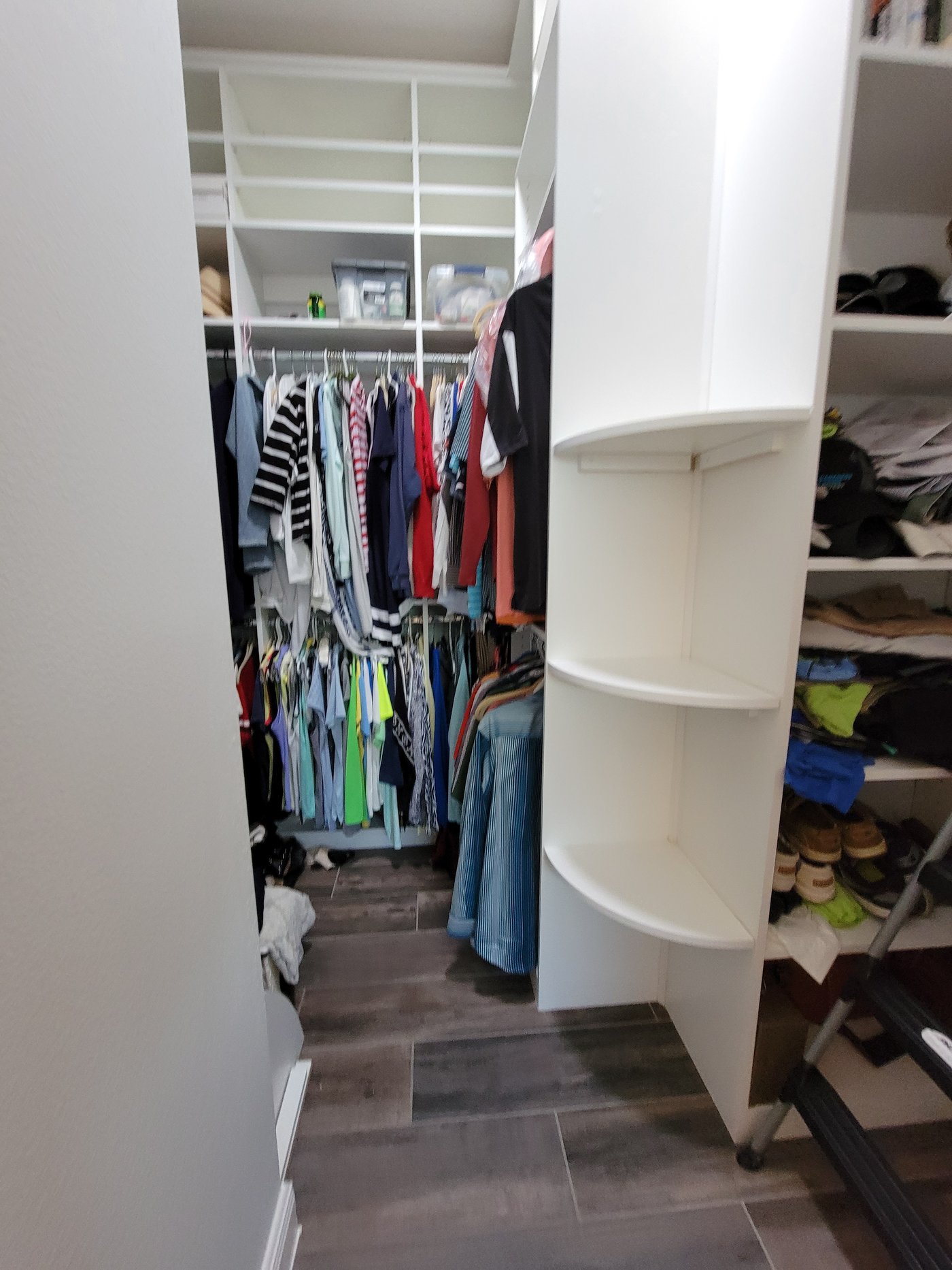 Walk-in closet with folded clothing and hanging sections by Create More Space