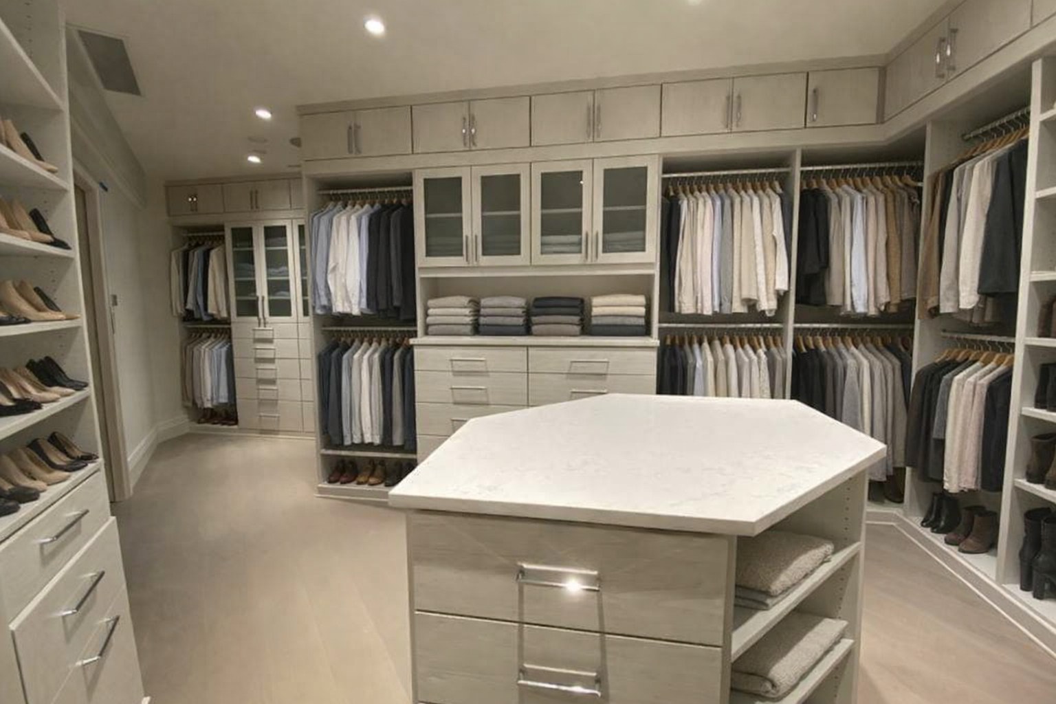 Large white walk-in closet with mirrored center island by Create More Space