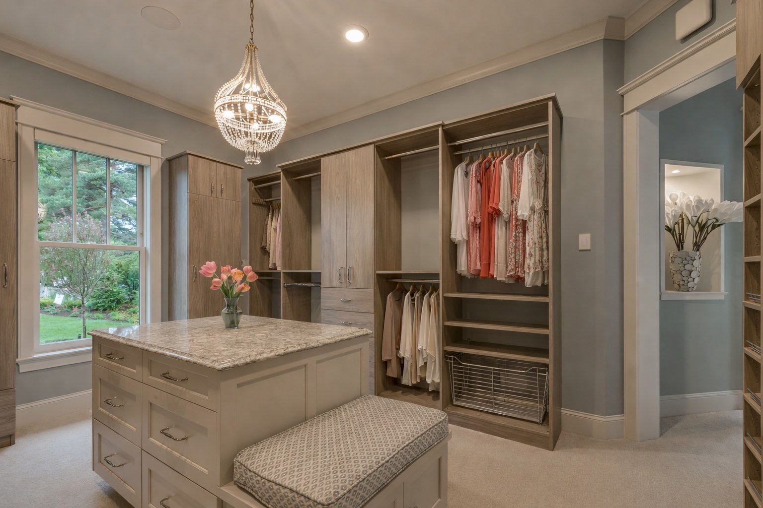Warm greige walk-in closet with marble island and window by Create More Space