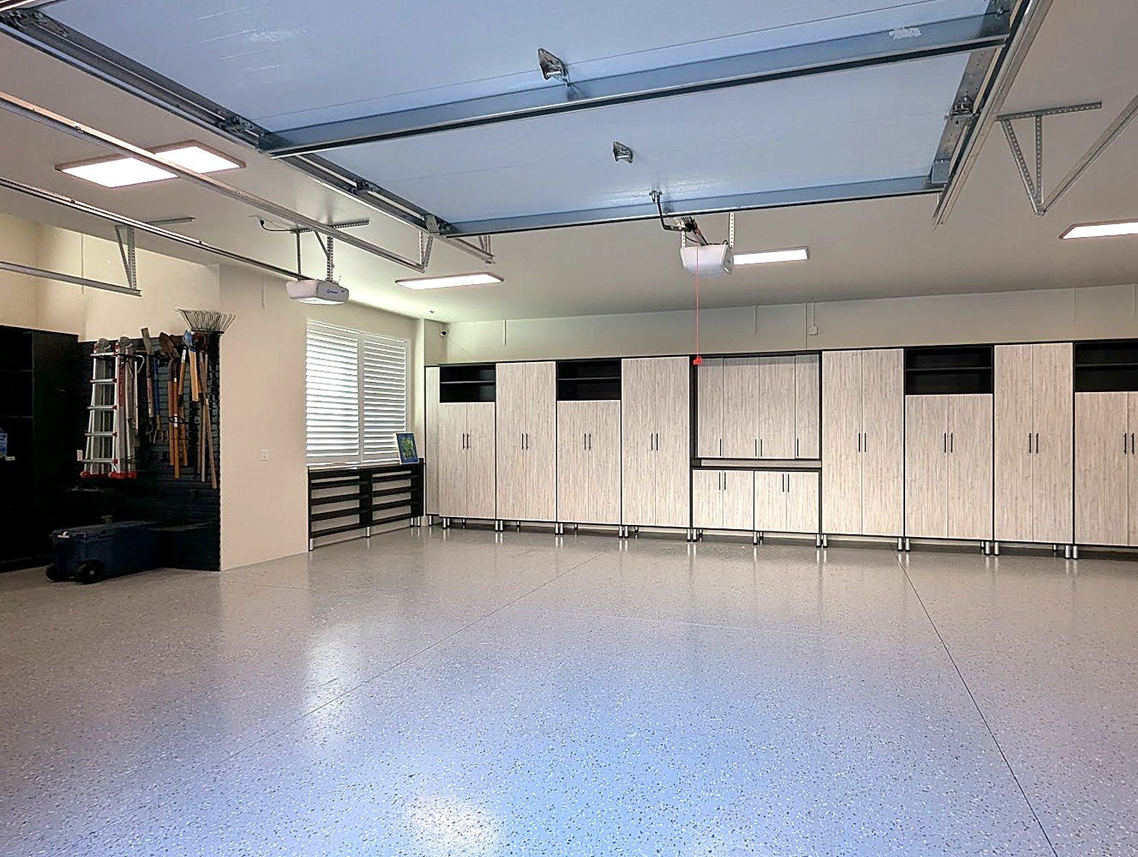Spacious custom garage with full cabinetry and epoxy floor by Create More Space