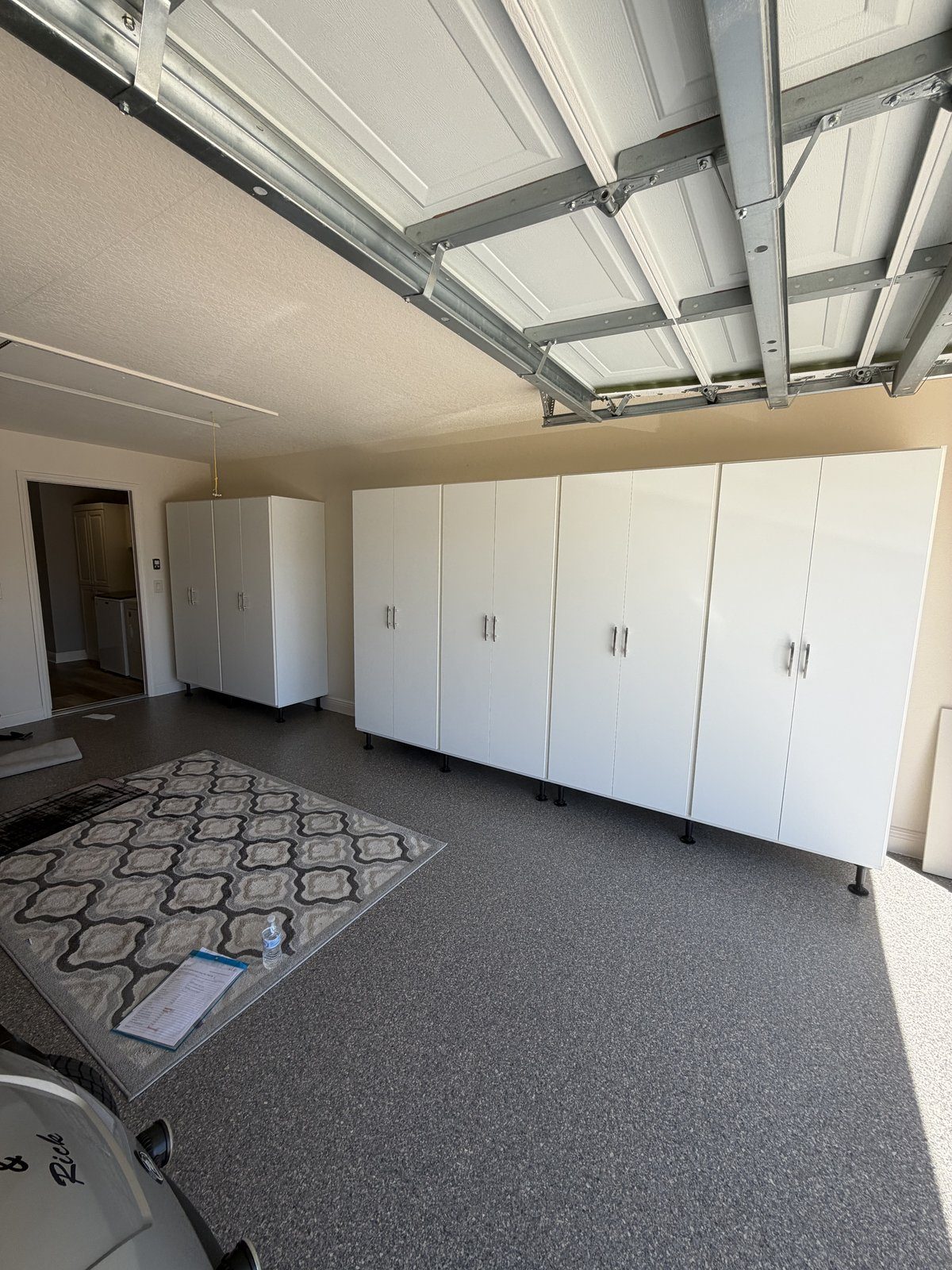 Full-wall white garage cabinetry with epoxy floor
